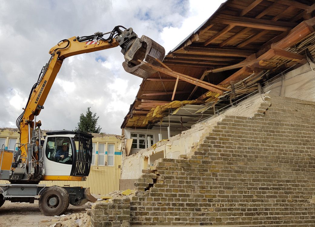 Bagger reißt altes Gebäude bei kontrolliertem Abriss ab