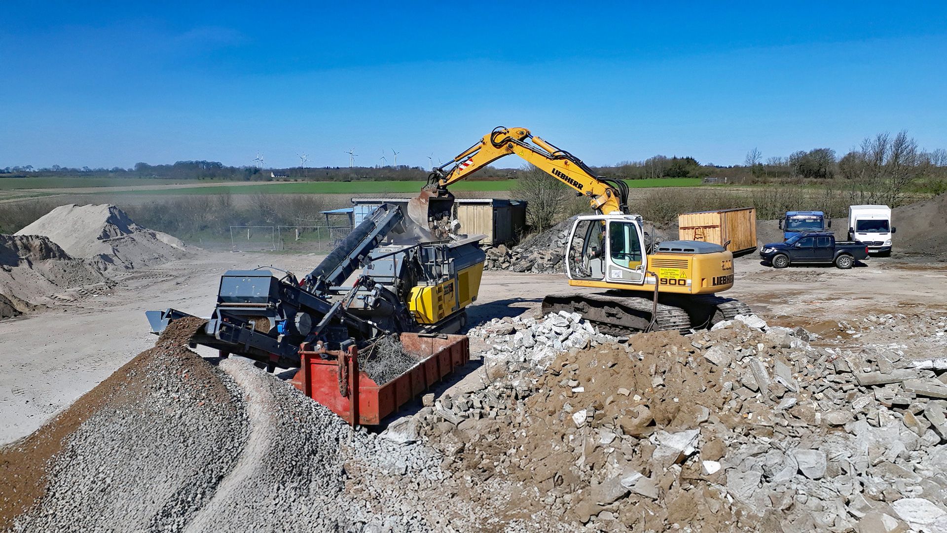 Bagger zerkleinert Betonabbruch auf Recyclingplatz im Außenbereich